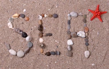Word sea made from sea shells and stones on sand