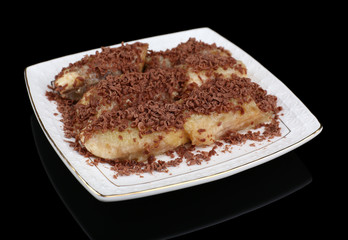 Sweetened fried banana on plate on black background, close-up