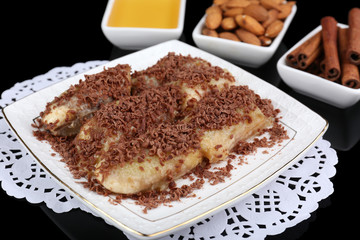 Sweetened fried banana on plate on black background, close-up