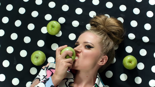 Fashion beauty portrait of blonde model biting an apple.