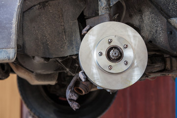 Front disk brake on car in process of damaged tyre replacement.