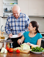  senior man and mature  woman cooking in  kitchen
