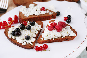 Bread with cottage cheese and berries on wooden tray close-up