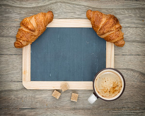 Coffee and croissant on a wooden board