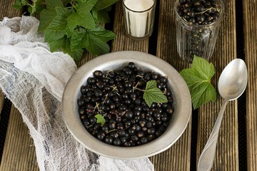 Black currants in a plate with sugar and leaves