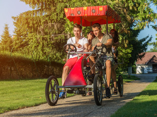 four young people in a four-wheeled bicycle