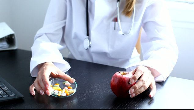 &Auml;rztin zeigt Apfel und Pillen