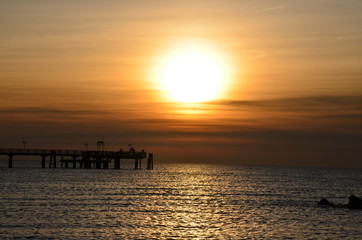 Angler auf Seebrücke bei Sonnenuntergang