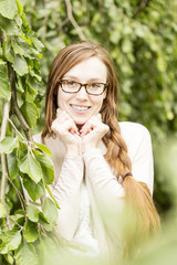 Frau mit roten Haaren und Brille vor natürlichem Hintergrund