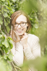 Frau mit roten Haaren und Brille vor natürlichem Hintergrund