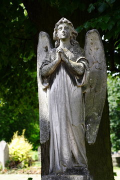 stone statue of woman angel with wings in cemetary	