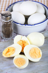 Boiled eggs on wooden board on tablecloth