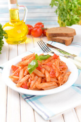 Pasta with tomato sauce on plate on table on light background