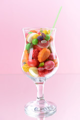 Different colorful fruit candy in glass on pink background