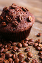 Chocolate muffin and coffee grains on wooden background