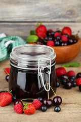 Tasty jam with berries in glass jar on wooden table © Africa Studio