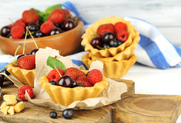 Tasty tartlets with berries on wooden table