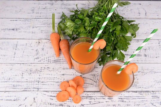 Glasses of carrot juice with fresh carrots and parsley