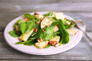 Green salad with apples, walnuts and cheese on wooden