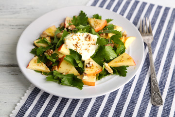 Green salad with apples, walnuts and cheese on wooden
