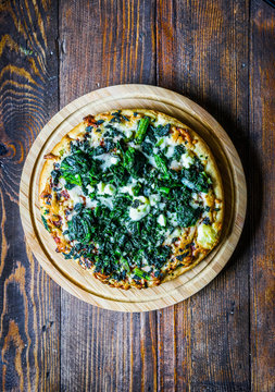 Spinach and goat cheese pizza on wooden background