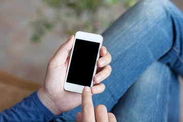 man sitting on a sofa and holding a white touch phone with a bla