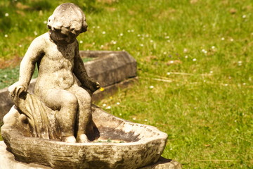 Fototapeta na wymiar stone Child Sculpture bird bath water fountain
