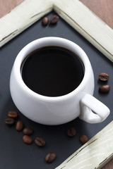 cup of coffee on black chalkboard close-up, top view