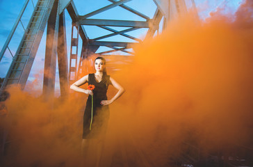 Girl on the old bridge in orange smoke