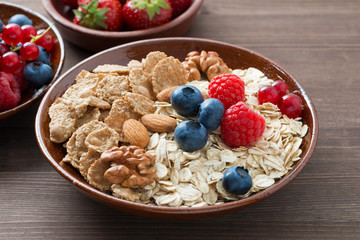 oatmeal and muesli in a bowl, fresh berries on wooden background