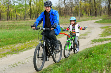 Happy father and child on bikes, family cycling outdoors
