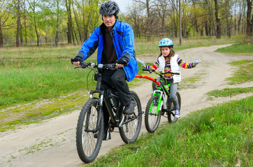 Obraz premium Happy father and child on bikes, family cycling outdoors