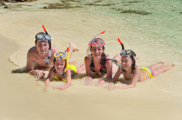 Happy family in snorkels on beach on sea vacation