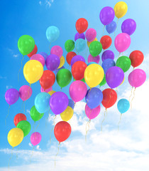 Flying balloons in blue sky with clouds