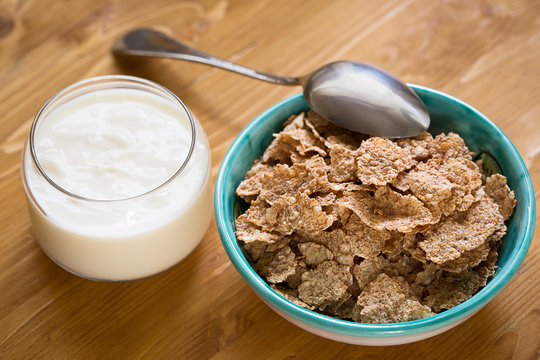Delicious and healthy wheat flakes in bowl with yogurt