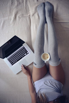 beautiful young woman sitting in bed with cup of coffee