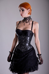 Pretty redhead young woman in silver corset and black skirt