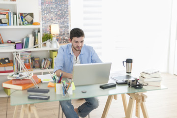 Fototapeta premium young student works on his laptop at home