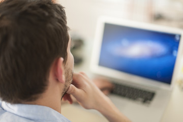 rear view of a man examining his computer's screen