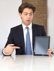 Businessman pointing to a tablet in horror