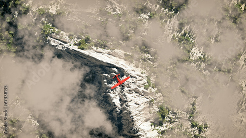 Red airplane flying over snow mountains with pine trees in the c
