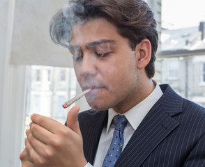 Young businessman lighting up a cigarette