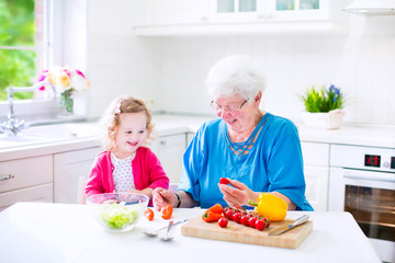 Obraz na płótnie Canvas Adorable grandmother and little girl making salad