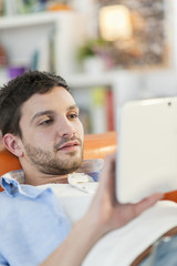 young student lying on a couch surfing  the web  on his digital