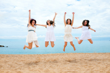 Four girlfriends jumping on beach