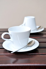 A cup of coffee on a wooden table in an outdoor cafe.