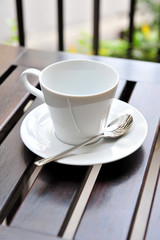A cup of coffee on a wooden table in an outdoor cafe.