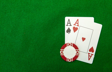 Cards showing pair of aces with chip on green background