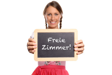 Junge Frau in einem Dirndl hält eine Tafel mit Text