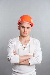 Portrait of a young confident worker in helmet isolated on grey